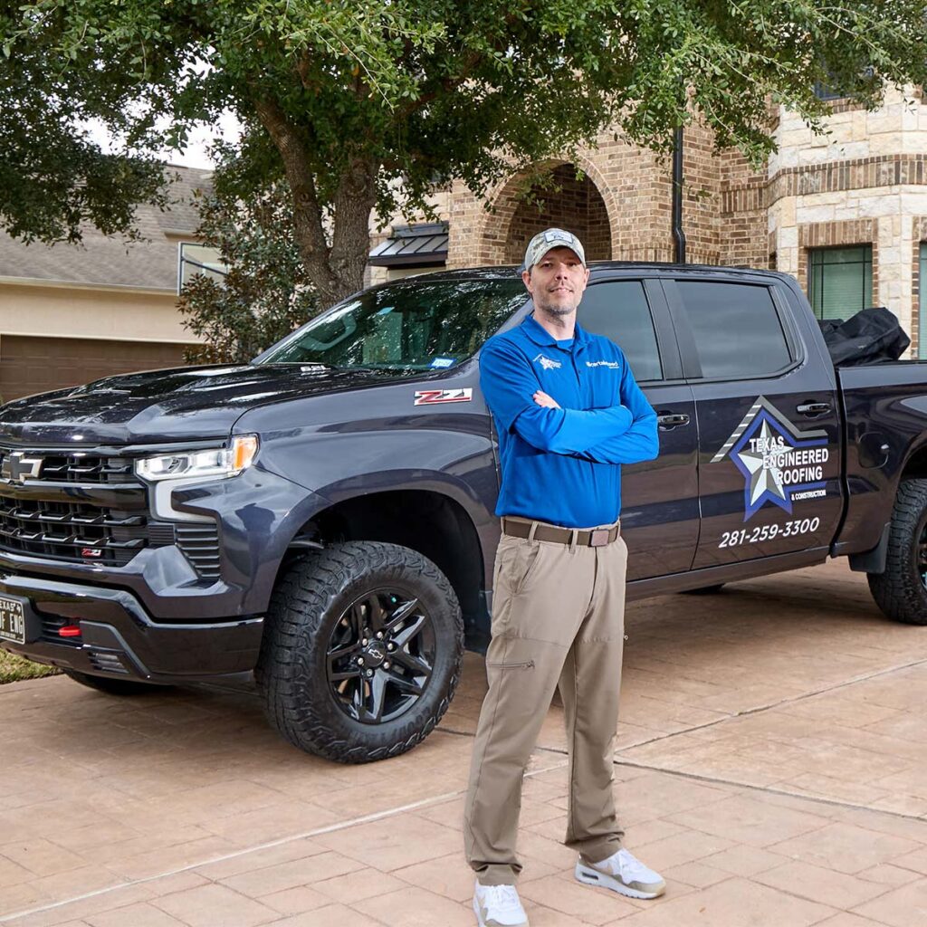 Brad of Texas Engineered Roofing standing with arms crossed beside a branded company truck