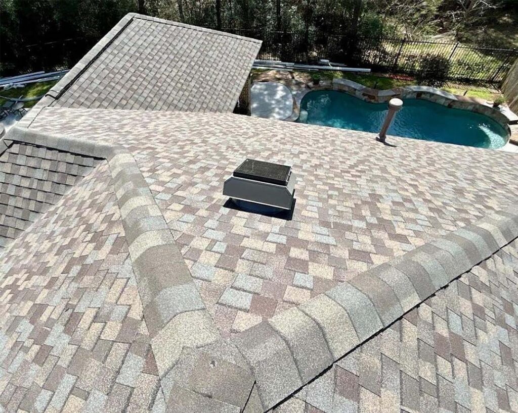 Solar attic fan installed on a tan shingle roof overlooking a backyard swimming pool