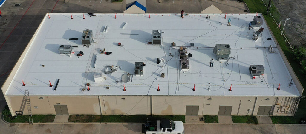 Aerial view of a large commercial building's white flat roof with rooftop HVAC units