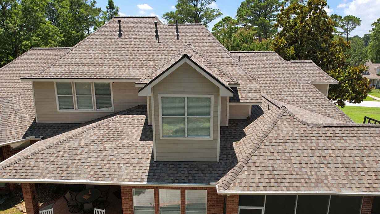 Tan architectural shingle roof with a center dormer on a two-story brick home, viewed from above