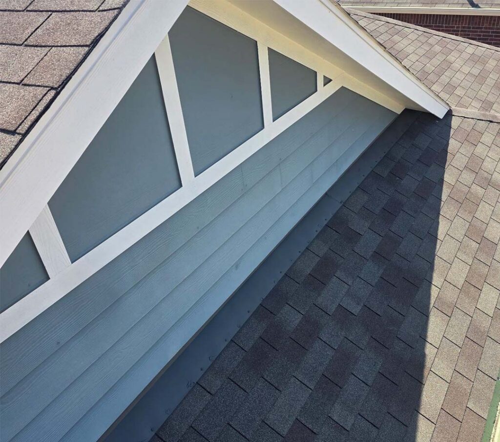 New architectural shingles installed along a gable wall with blue siding and white trim