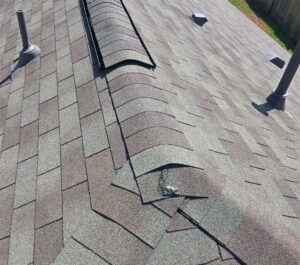 Close-up of a new architectural shingle roof showing the ridge cap, vent, and pipe flashing