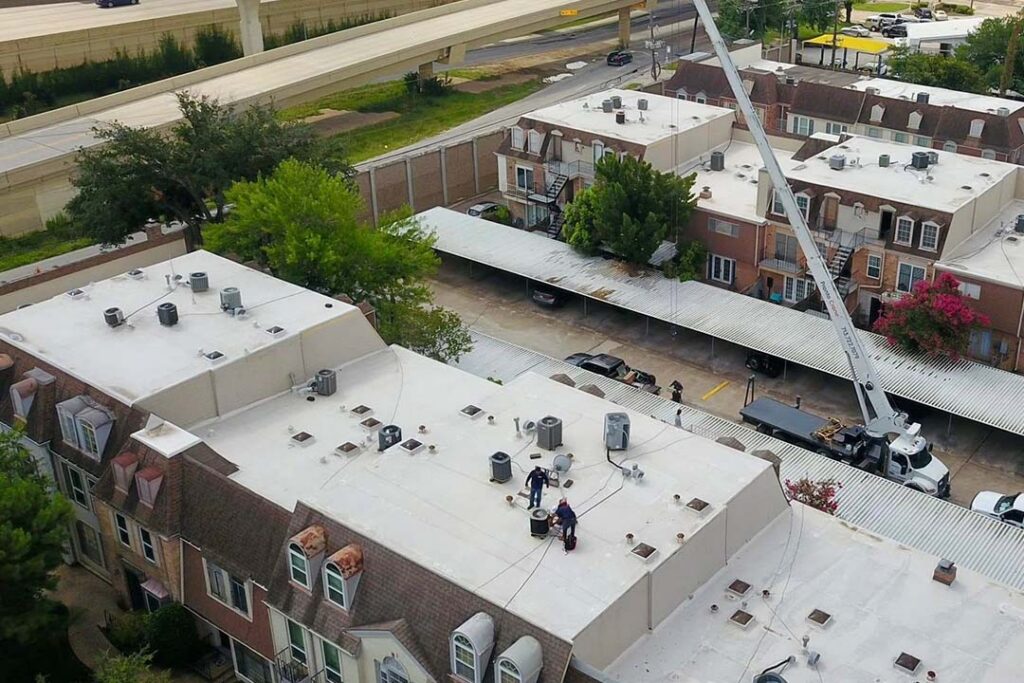 Crane lifting materials onto the flat roofs of a multi-family apartment building during a roof replacement
