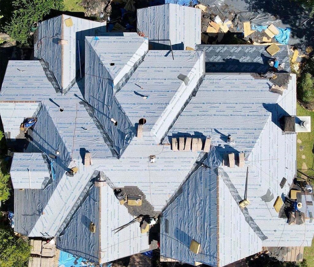 Aerial view of a roof replacement in progress with synthetic underlayment installed across the entire roof deck